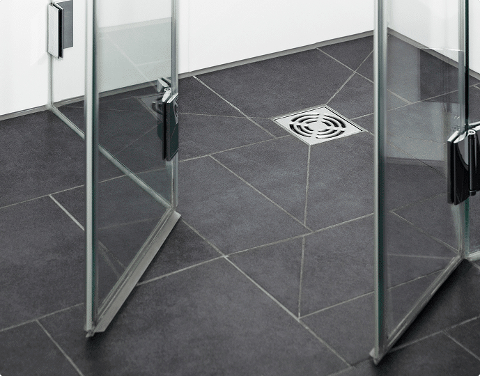 Shower floor with dark tiles, glass panels, and a central drain.