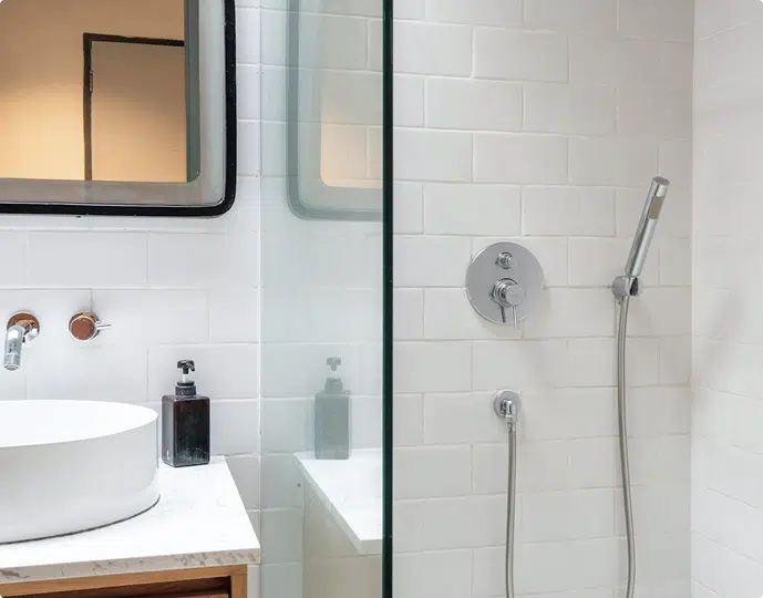 Modern compact bathroom with white subway tiles, frameless glass shower screen, timber vanity, and vessel sink.
