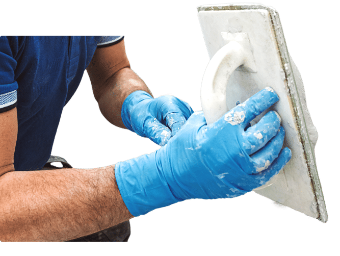 Worker wearing gloves applying plaster with a trowel.
