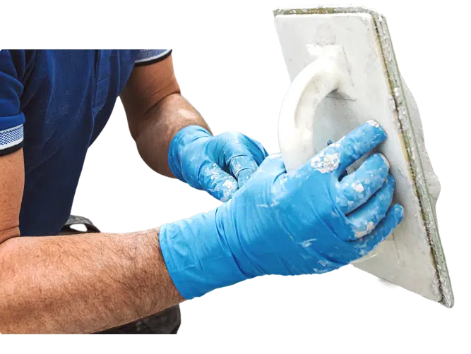 Worker wearing gloves applying plaster with a trowel.
