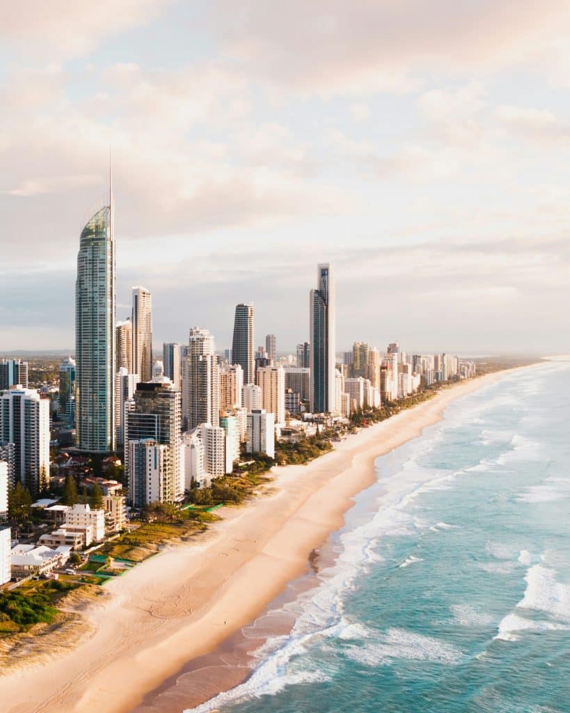Aerial view of Gold Coast beachfront with high-rise buildings, sandy beach and ocean waves along the coastline.